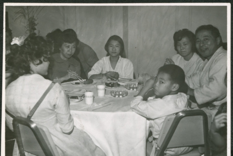 Group of adults and one child sitting at a table eating (ddr-densho-293-179)