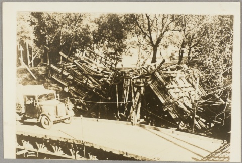 A truck crossing a bridge next to debris from a bombing (ddr-njpa-13-1066)