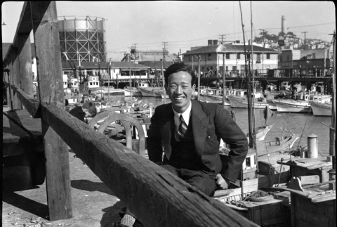 Man sitting by harbor with small boats (ddr-densho-426-2181)