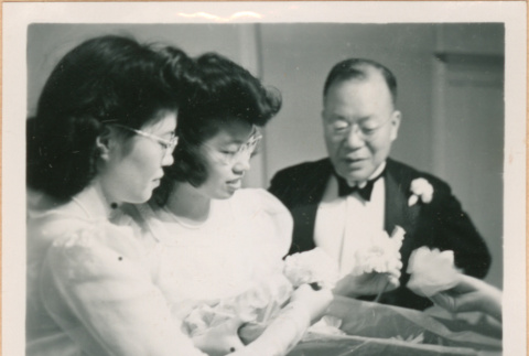 Tomoye (Nozawa) Takahashi and Martha Nozawa with unidentified man looking at a box of flowers (ddr-densho-410-522)