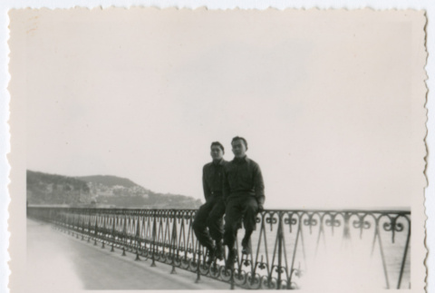 Soldiers sitting on railing of boardwalk near waterfront (ddr-densho-368-236)