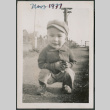 Photo of a toddler in a jacket and hat squatting (ddr-densho-483-704)