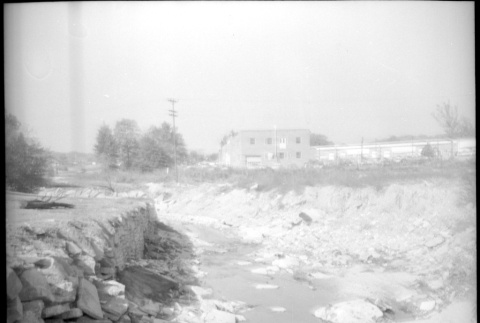 Small rocky stream with buildings in background (ddr-densho-377-1508)