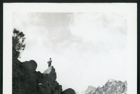 Photograph of a person standing on a rock in the snow-covered mountains (ddr-csujad-47-294)