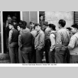 Men standing in line outside building (ddr-ajah-2-787)
