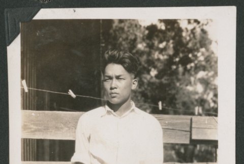 boy leaning against a fence (ddr-densho-378-536)