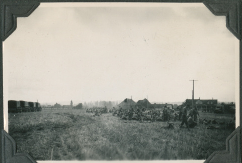 Men sitting in field with row of trucks (ddr-ajah-2-238)