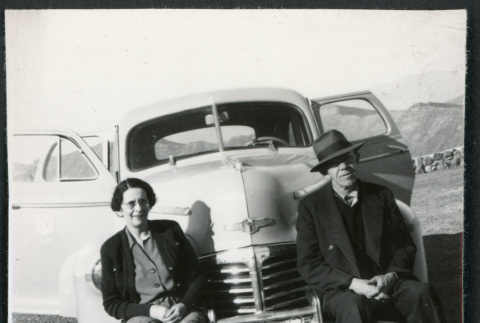 Photograph of B. R. and Theo Chamberlain sitting on the front bumper of their car in Death Valley (ddr-csujad-47-113)