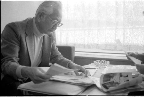 Harry Fukuhara looking through papers (ddr-densho-1007-1167)