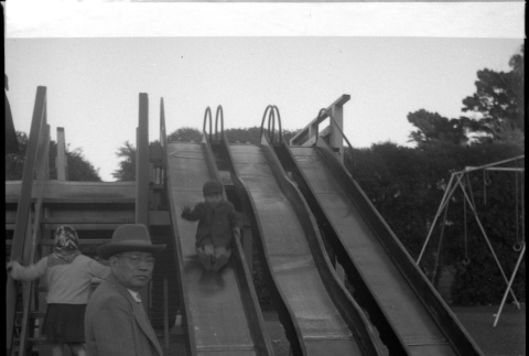Man standing by slide with two children (ddr-densho-426-927)