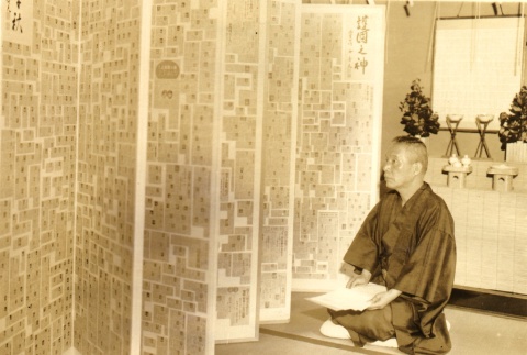 A man seated next to a collection of news clippings (ddr-njpa-4-2434)