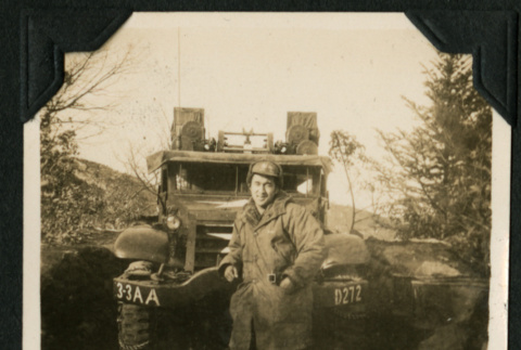 Walter Matsuoka leans against a military vehicle (ddr-densho-390-91)