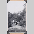 Photo of three people sitting on river rocks (ddr-densho-483-452)