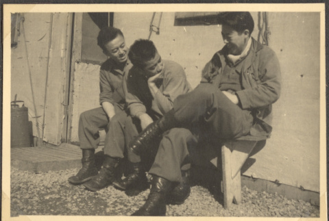 Three men sitting on bench outside building (ddr-densho-466-38)