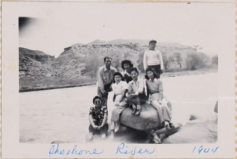 Group sitting on boulder alongside river (ddr-densho-464-33)