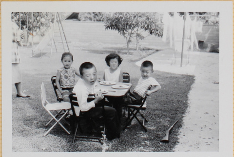 Four children sitting a table in a yard (ddr-densho-522-406)