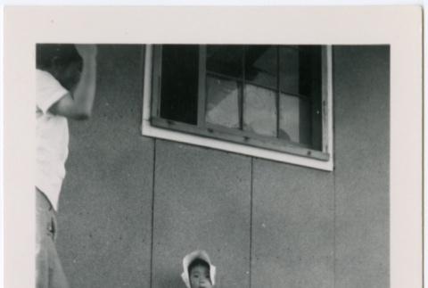 Little girl in bonnet outside barracks (ddr-densho-329-962)