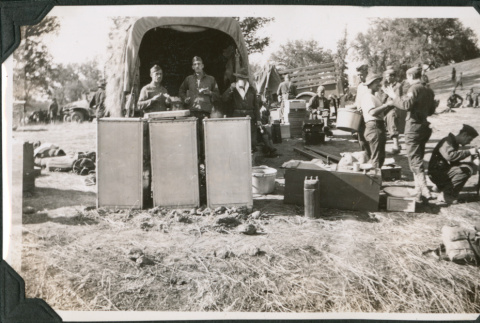 Men standing by truck with kitchen boxes, eating (ddr-ajah-2-187)
