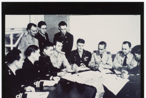Figures gathered around paper-covered table (ddr-densho-1007-196)