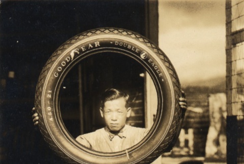 Hiroshi Takeshita holding up a car tire (ddr-njpa-4-1202)