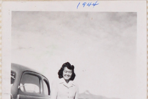 Woman standing next to car, Heart Mountain in background (ddr-densho-464-41)