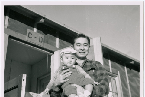 Paul Nakadate with baby in front of barracks (ddr-densho-122-654)