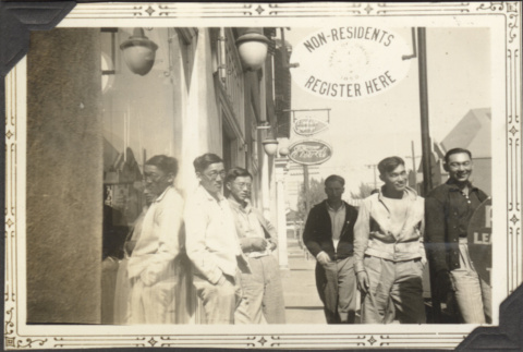 Five men standing by sign 