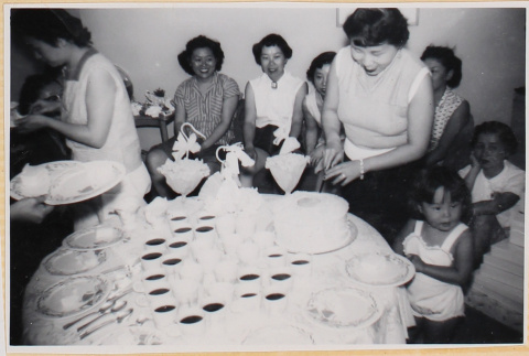 Woman cutting a cake at a party with women and children (ddr-densho-522-27)