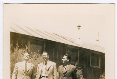 Three men in suits standingin front of barracks (ddr-densho-223-40)
