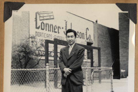 Man standing in front of a sign (ddr-densho-542-150)