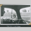 Man behind wheel of car driving past rows of tents (ddr-densho-434-320)
