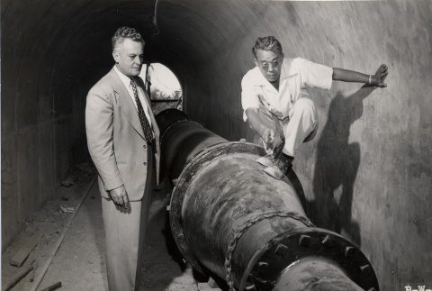 Two engineers examine a water main in the Fort Ruger tunnel (ddr-njpa-2-729)