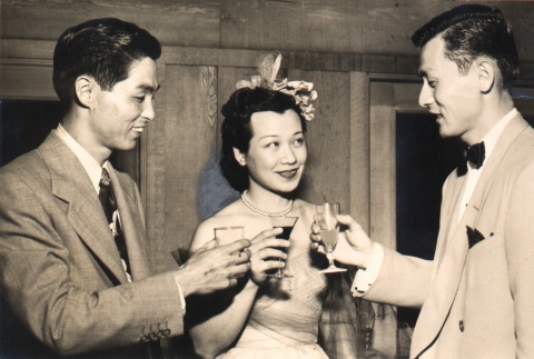 Two men and a young woman toasting with drinks (ddr-njpa-4-25)