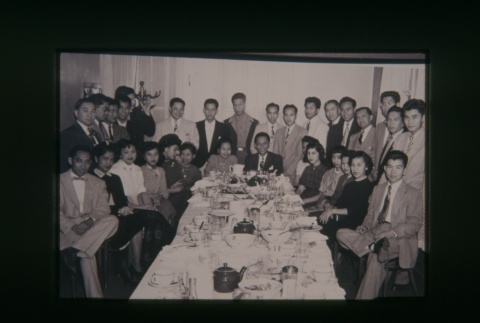 (Slide) - Image of men and women seated & standing around table (ddr-densho-330-200-master-103669558f)