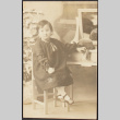 Young girl posing at a desk with Christmas tree (ddr-densho-278-77)
