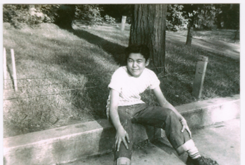 Frank Nishioka sitting on curb (ddr-densho-292-62)