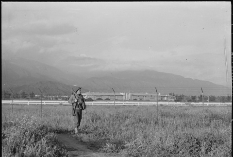 Military policeman patrolling camp fence (ddr-densho-37-483)