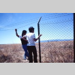 Two pilgrims standing next to a barbed wire fence at Tule Lake (ddr-densho-294-50)