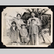 Family of five poses in front of an evergreen tree (ddr-densho-404-90)