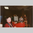 Tomoye and Henri Takahashi standing by table with gifts, woman in foreground (ddr-densho-426-1298)