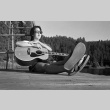 Brad Shirakawa sitting on the dock with a guitar (ddr-densho-336-1937)