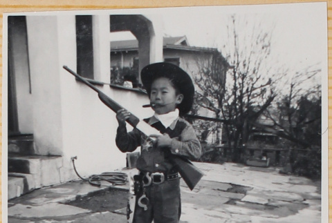 William Shiomi in cowboy costume with toy gun (ddr-densho-522-258)