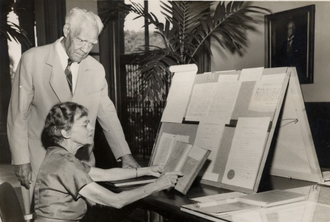 A librarian shows a book to a Honolulu businessman and politician (ddr-njpa-2-464)