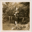 Tomoye (Nozawa) Takahashi holding cat in garden (ddr-densho-426-2120)