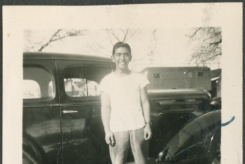 A young man standing in front of a car (ddr-densho-298-59)