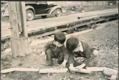 Two boys playing with a toy car (ddr-densho-523-111)
