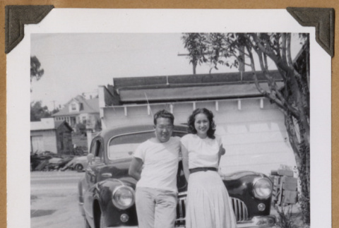 Man and woman lean against a car (ddr-densho-542-75)
