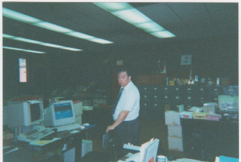 Dave Sato standing in office (ddr-densho-426-1212)