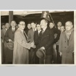 Two men shaking hands in front of a group (ddr-njpa-1-1741)