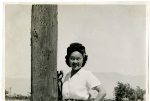 Woman standing next to a telephone pole (ddr-manz-6-23)